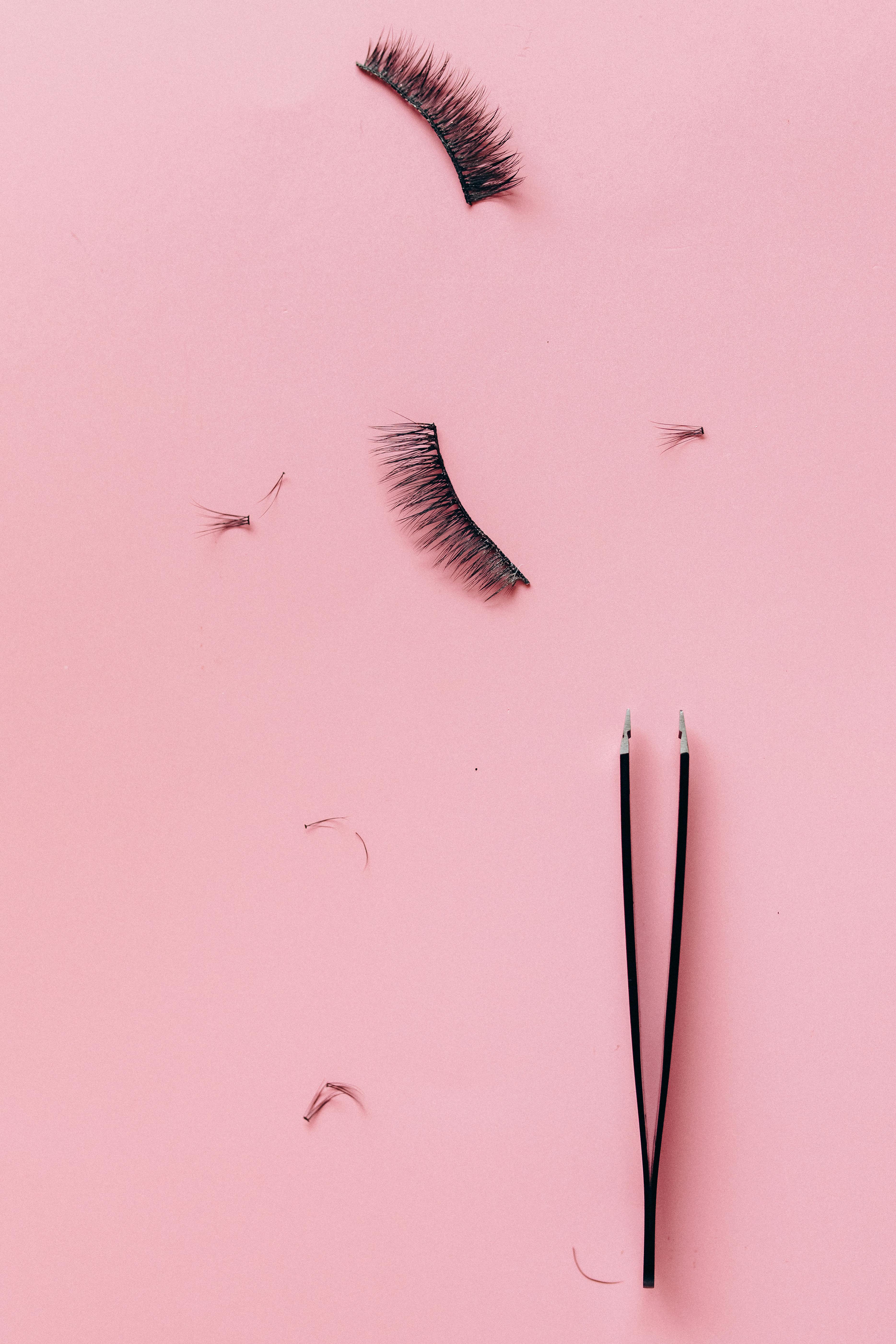 False Eyelashes Beside the Tweezers on Pink Surface